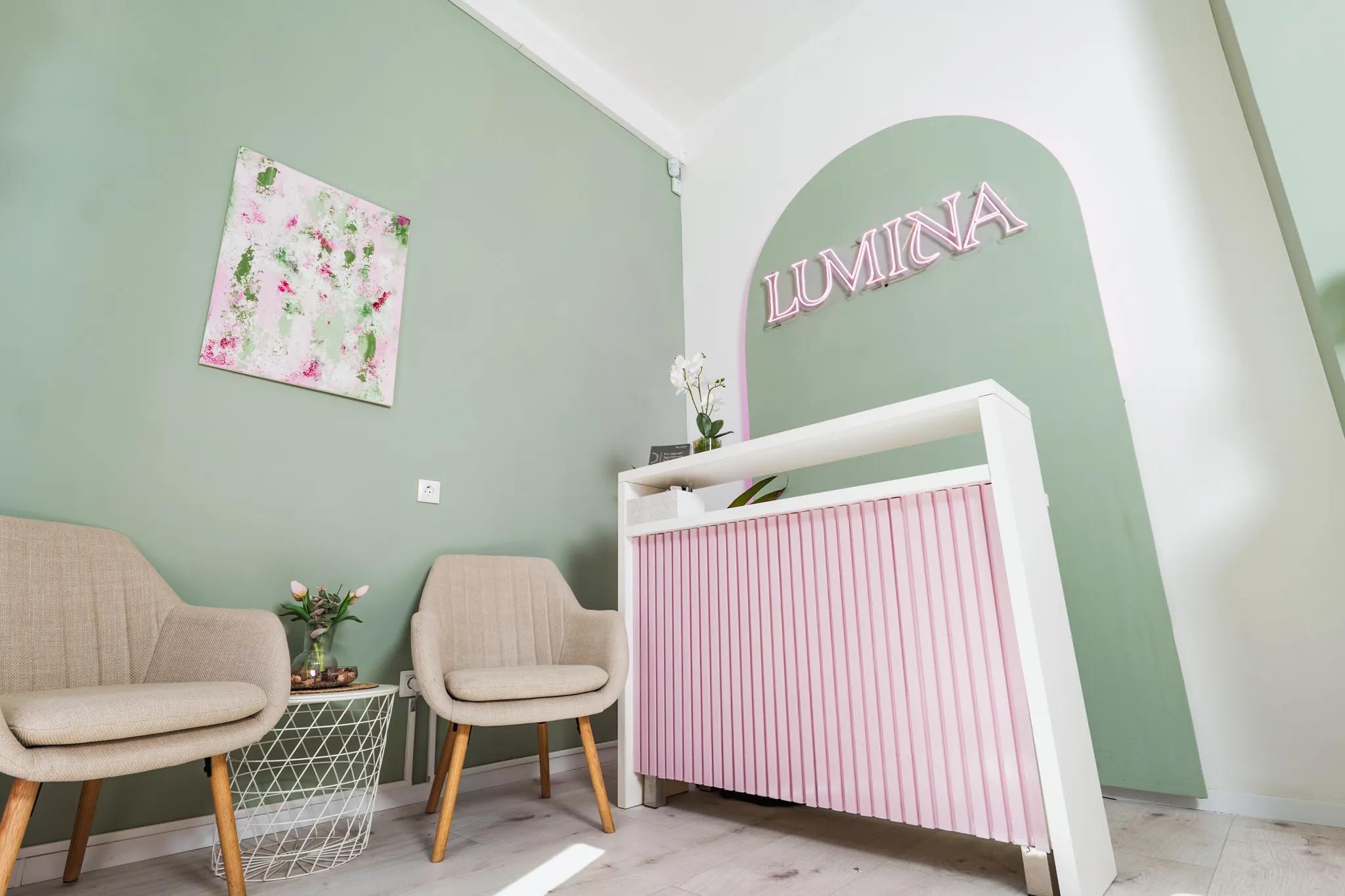 A Lumina szalon zsályazöld fala, rózsaszín pult és a Lumina neonfelirat